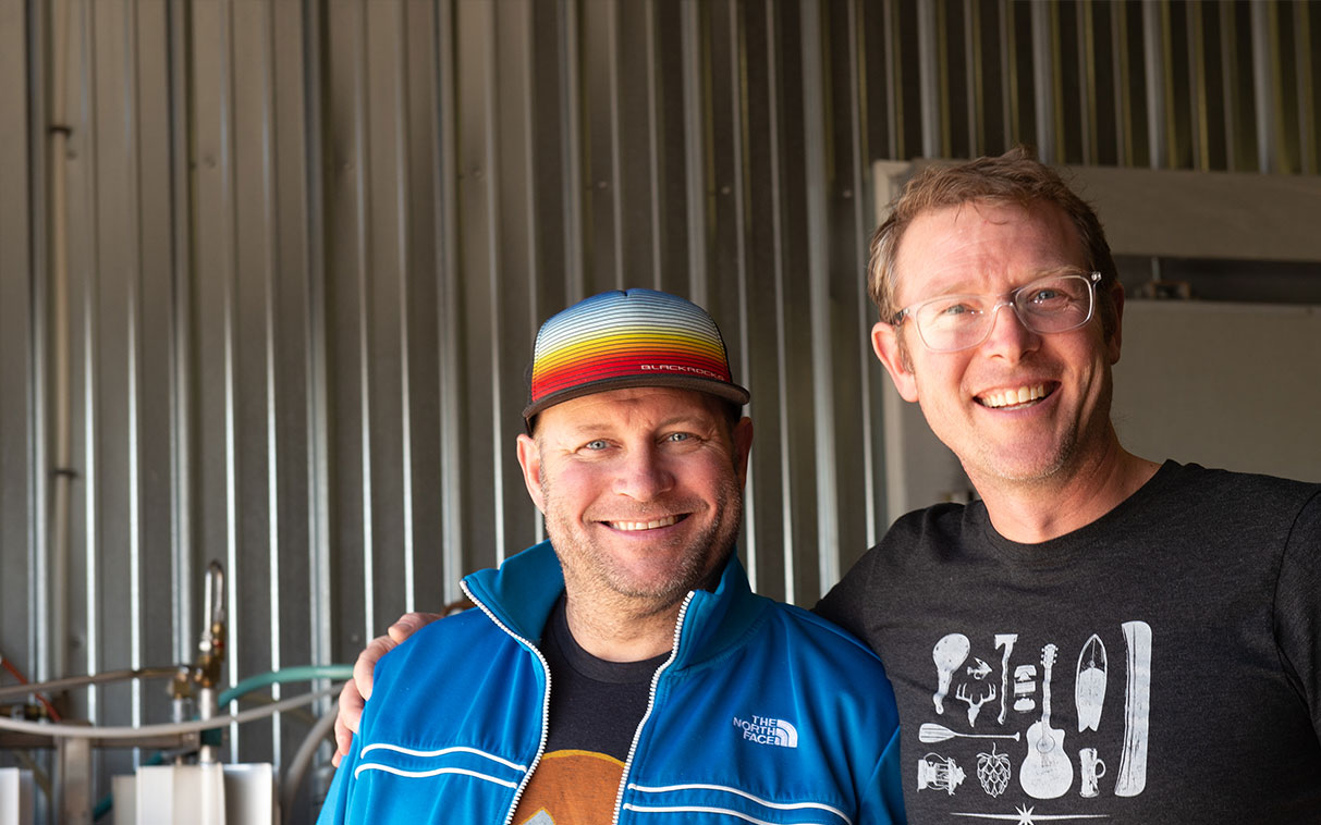 two smiling men working at a brewery