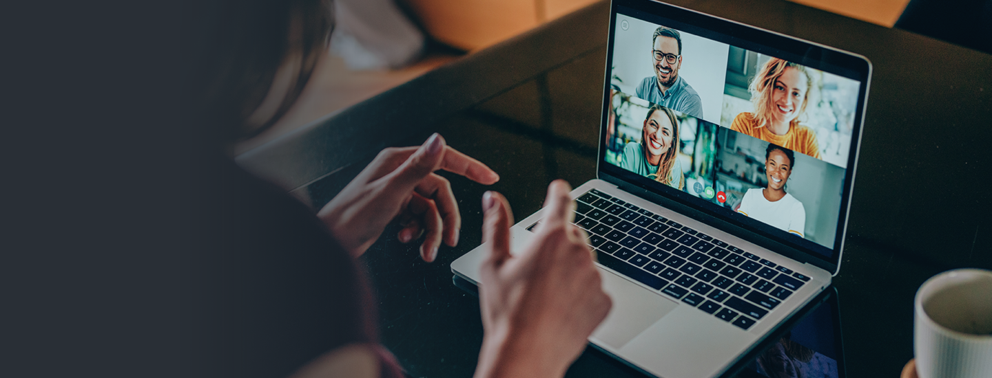 A woman in a virtual meeting on a laptop with four people on the screen.