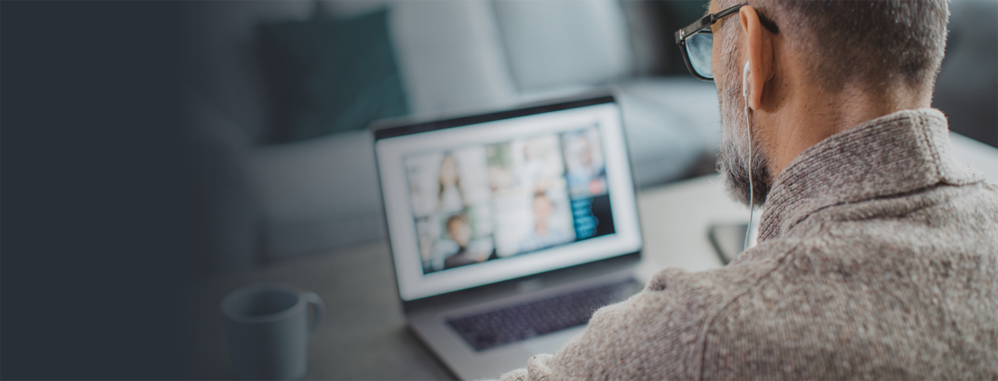An over-the-shoulder view of a man on a laptop.