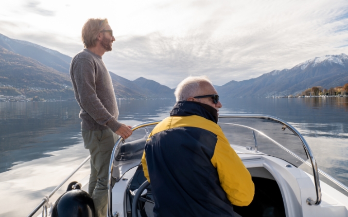 Two men in a boat on the water surrounded by mountains