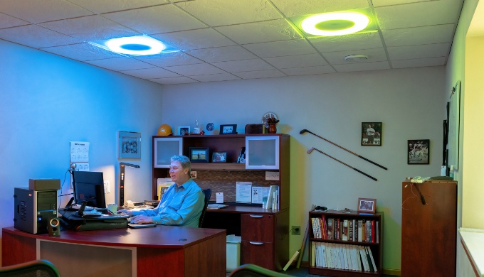 Rod Heller of Energy Performance Lighting at his desk with circular colored lights above him