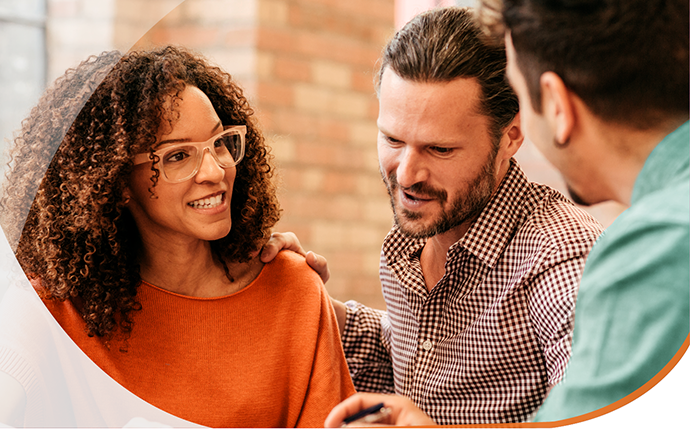 A woman talks to two men as they look at paperwork.