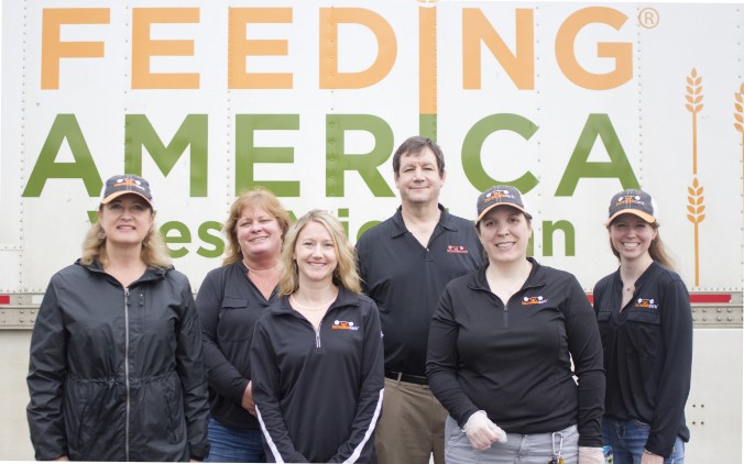 Group photo of IncredibleBank employees in front of a banner for Feeding America when they volunteered.