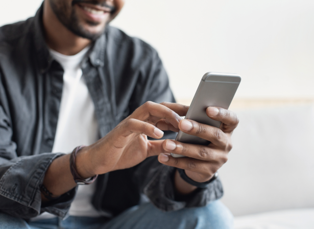 Un hombre con un teléfono en la mano sentado en el sofá