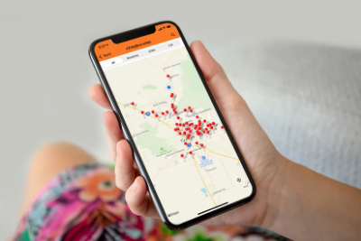 Person holding a phone showing a map with many dots indicating locations on the map