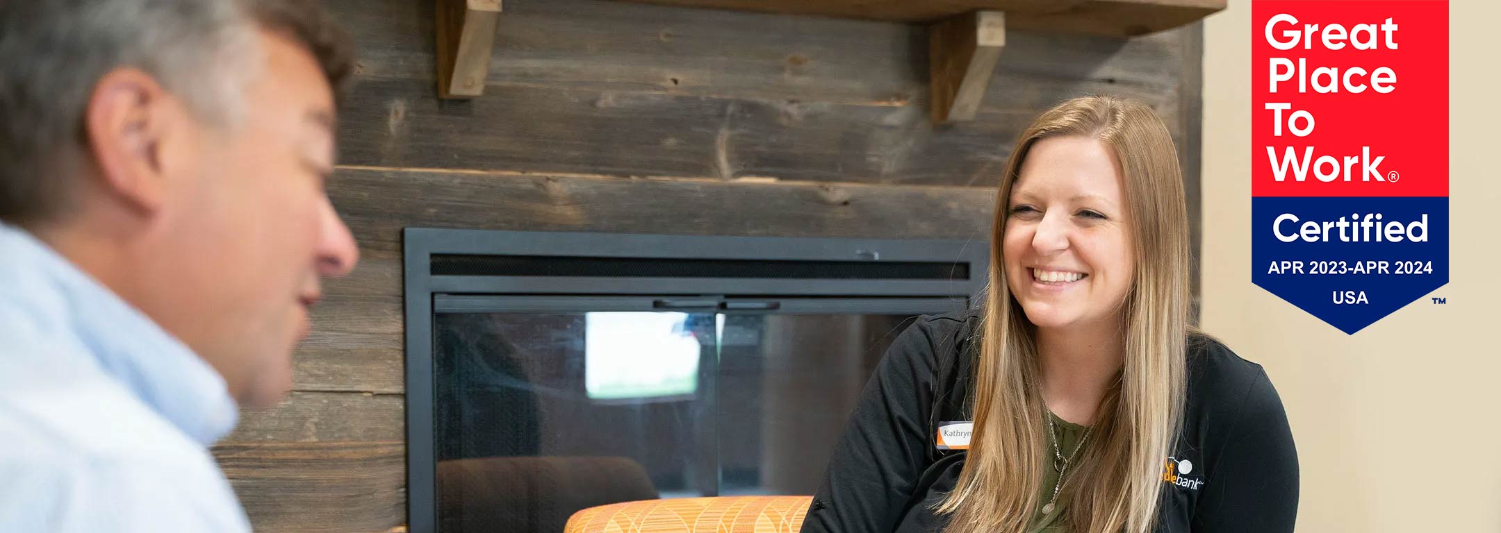 A female IncredibleBank employee smiles at a male customer.