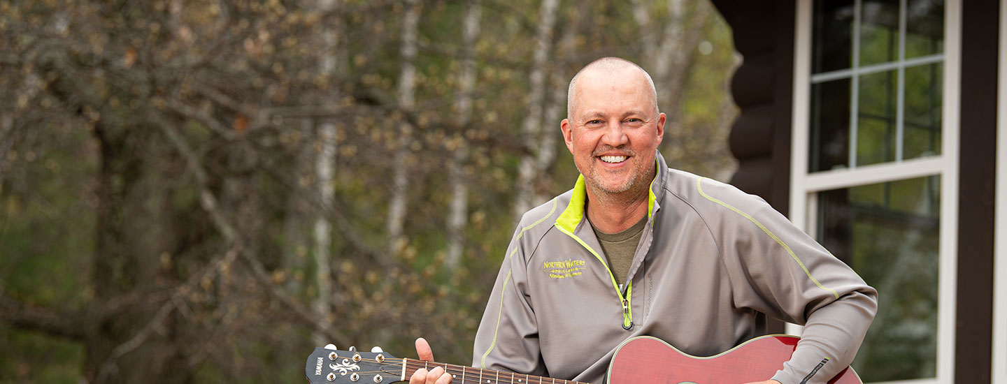 business owner playing guitar outside