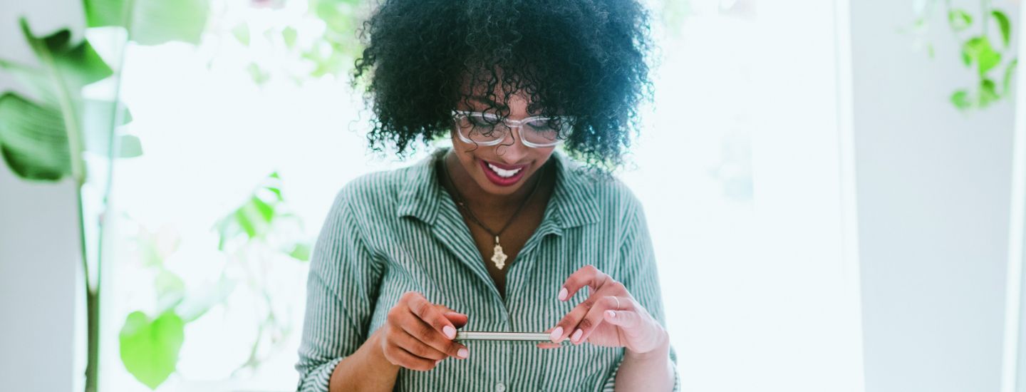 Una mujer con gafas usando el depósito móvil para tomar una foto de un cheque
