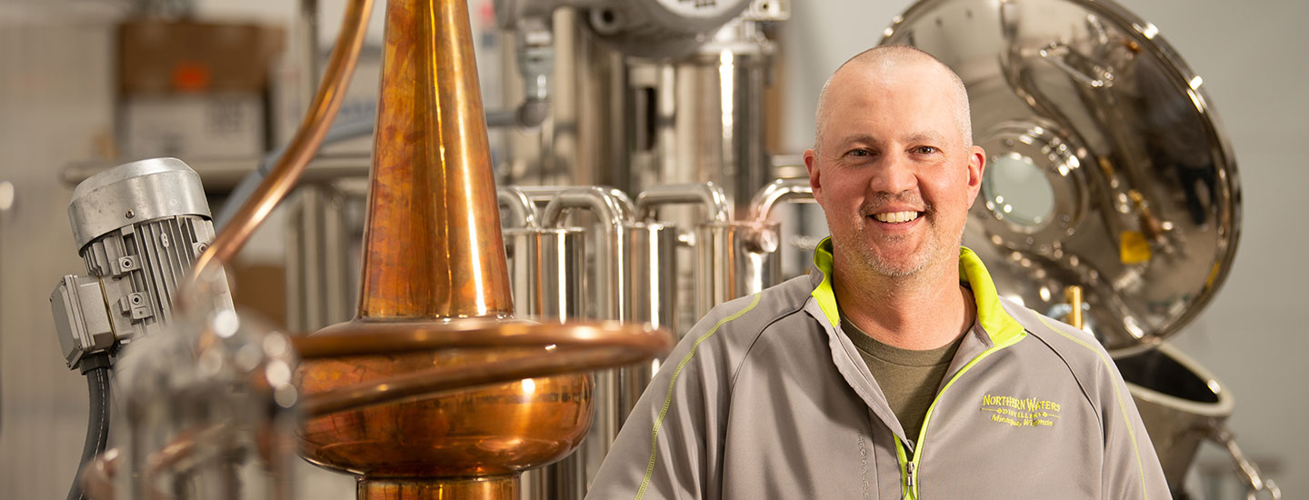 Owner of a distillery in front of his equipment