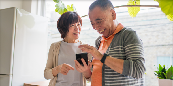 Woman and man in kitchen smiling and holding a phone