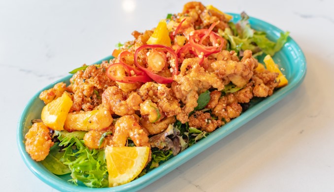 A plate of fresh seafood with greens and citrus.