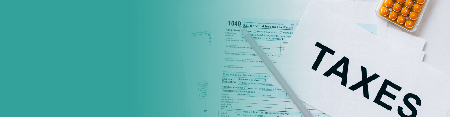 Paperwork, a calculator, and a pencil with a sheet of paper that says "taxes" on it