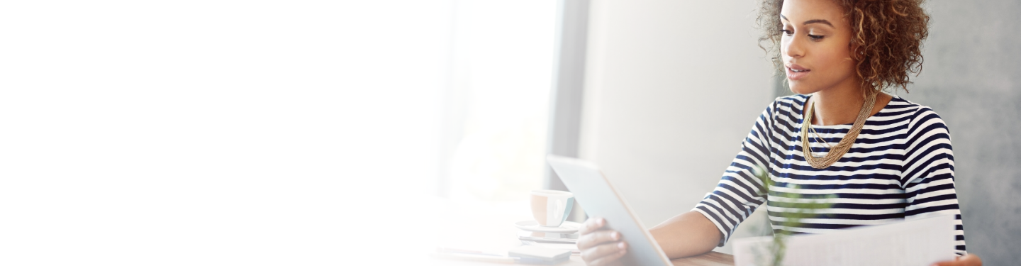 Woman looking at tablet in one hand and paper in the other